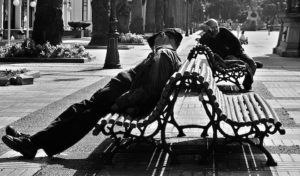 Photo of men sleeping while sitting on public benches.