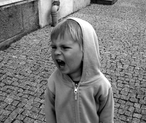 Photo of little boy screaming and shouting with an angry face.