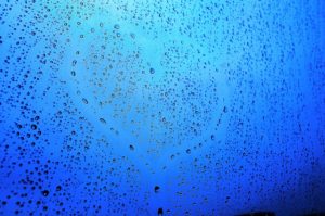 A heart etched out on a window covered in water droplets
