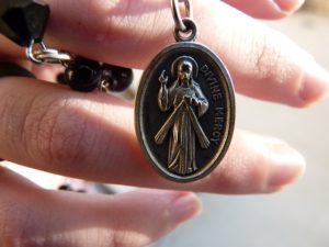 A rosary with an image of Jesus giving mercy