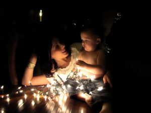 A mother and child lit by a string of Christmas lights