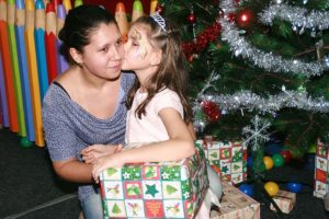A child receiving Christmas gifts from their mother.