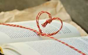 An open book tied with string wrapped around it in the shape of a heart.