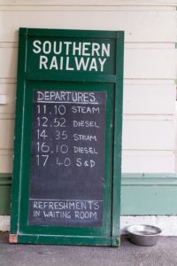 A railway timetable written on a chalkboard.