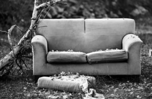 A black and white photo of a torn up old couch.