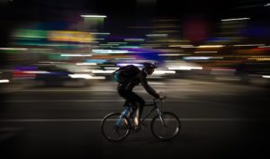 A bicycle courier with a backdrop of city lights.