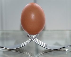 An egg balanced on two forks.