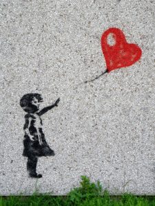 Art of a girl reaching for a heart shaped balloon that is floating away.