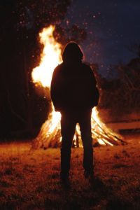 A bonfire burning against the silhouette of a person.