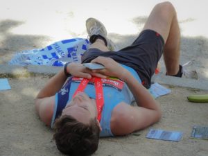 A fatigued runner lying on the side of the path during a marathon.