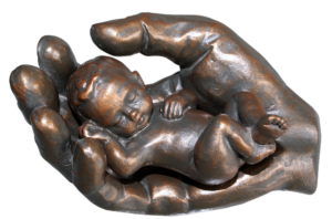 Sculpture of a child in the cradled hand of God.