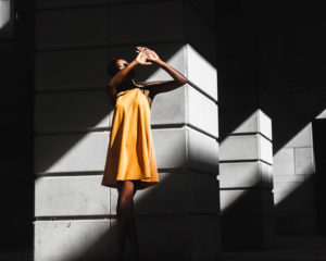 A person standing in shadow while shielding their face from a ray of light.