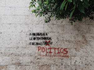 Words about lies, truth, and politics spray painted on a wall in the street.
