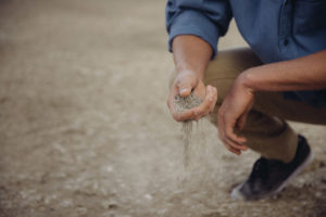 A man sifting sand through his fingers.