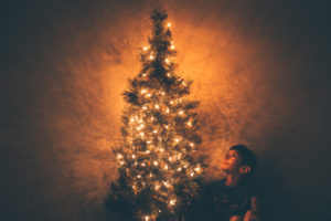 A child looking up at the splendor of a lit Christmas tree.