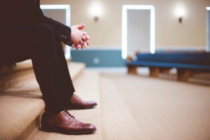 A person waiting at the front of an empty church sanctuary as if forgotten.