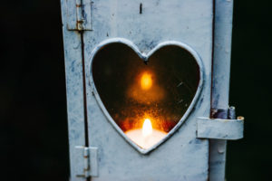 A lit flame in a heart shaped window.