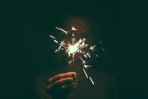 A person holds up a sparkler lighting up the dark.