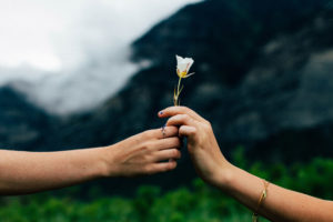 A person blessing another by passing a flower to them.