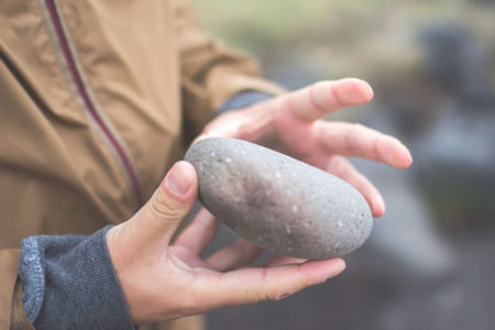 A person gathering a large stone in their hands.