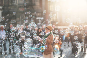 A person surrounded by people, sharing the experience of many floating bubbles.
