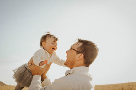 A father holding up his laughing child.