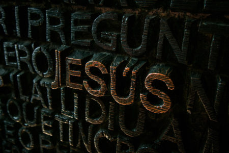 The name of Jesus carved out in wood.