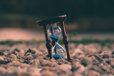 An hourglass sitting on stone-covered ground.