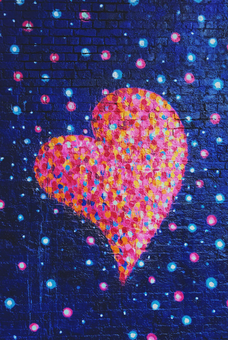 A large graffiti heart on a brick wall.