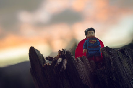 Lego Superman on a tree stump.
