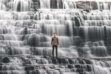 A man standing in front of cascading waterfalls.