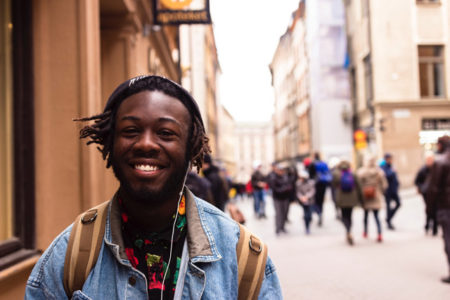 A man smiling as he walks along a busy city street.
