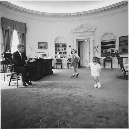 President Kennedy clapping as his children dance in the Oval Office.
