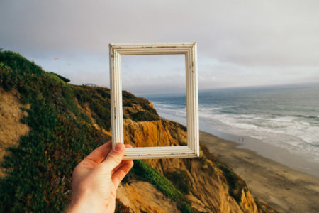 An empty frame held against an ocean landscape.