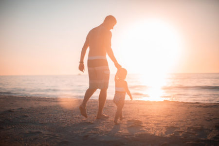 A father walking with his son on the beach.