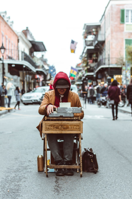 A man sitting at a typewriter in the middle of a busy street.