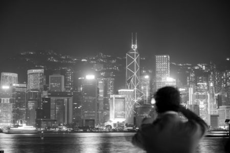 A man surveying the Hong Kong skyline at night.