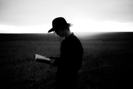 A man reading a book outside.