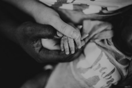 Parents holding a baby's hand.