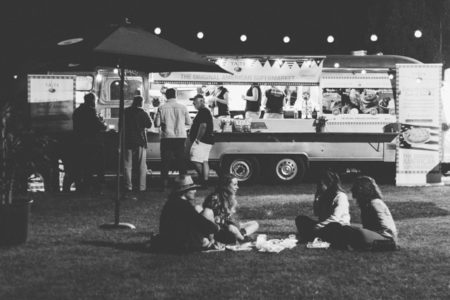 People sitting in a circle next to a food truck.