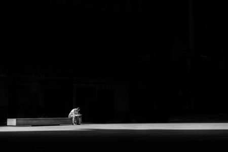 A man sitting on a bench, praying.