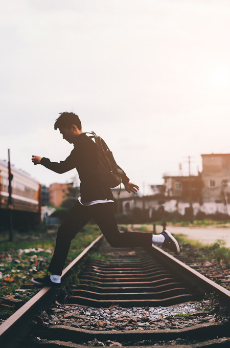 A man skipping across train tracks.