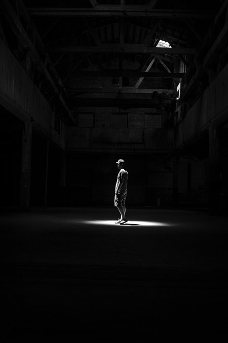 A man under a spotlight in a warehouse.