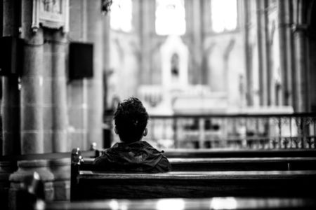 A person sitting in the pews of a large church.