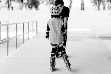 A kid learning to rollerblade.