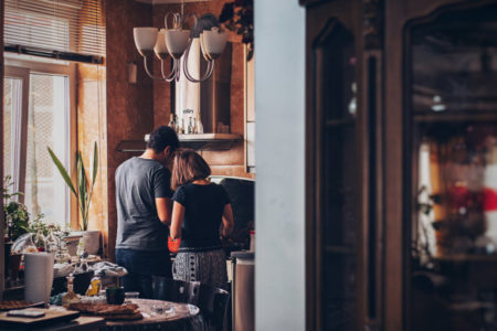 A husband and wife working in the kitchen.