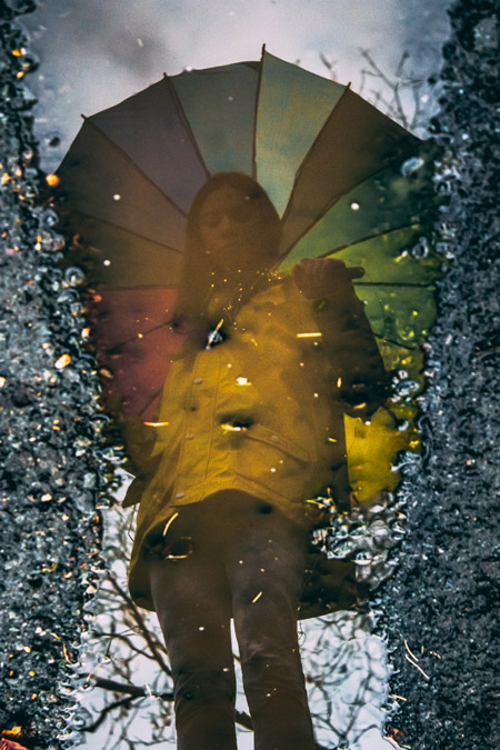 A woman's reflection in a rain puddle.